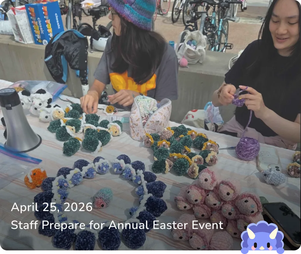 April 25, 2026 — Staff Prepare for Annual Easter Event: members arranging rows of crocheted dinos on a table.