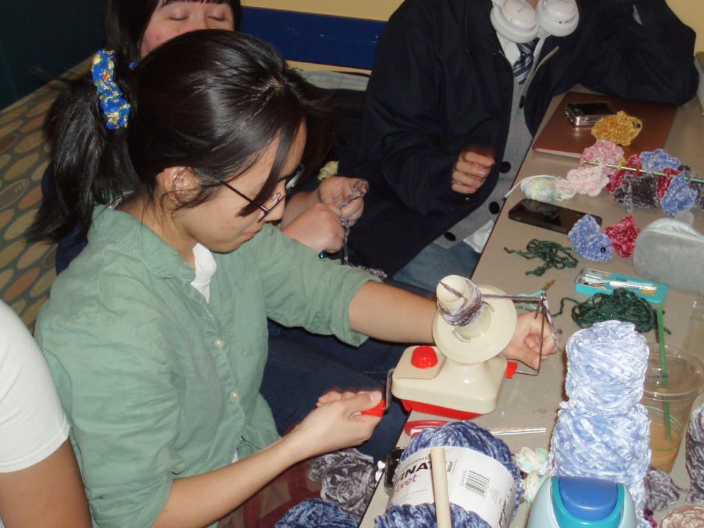 A member winding yarn at a table covered in crocheted dinos