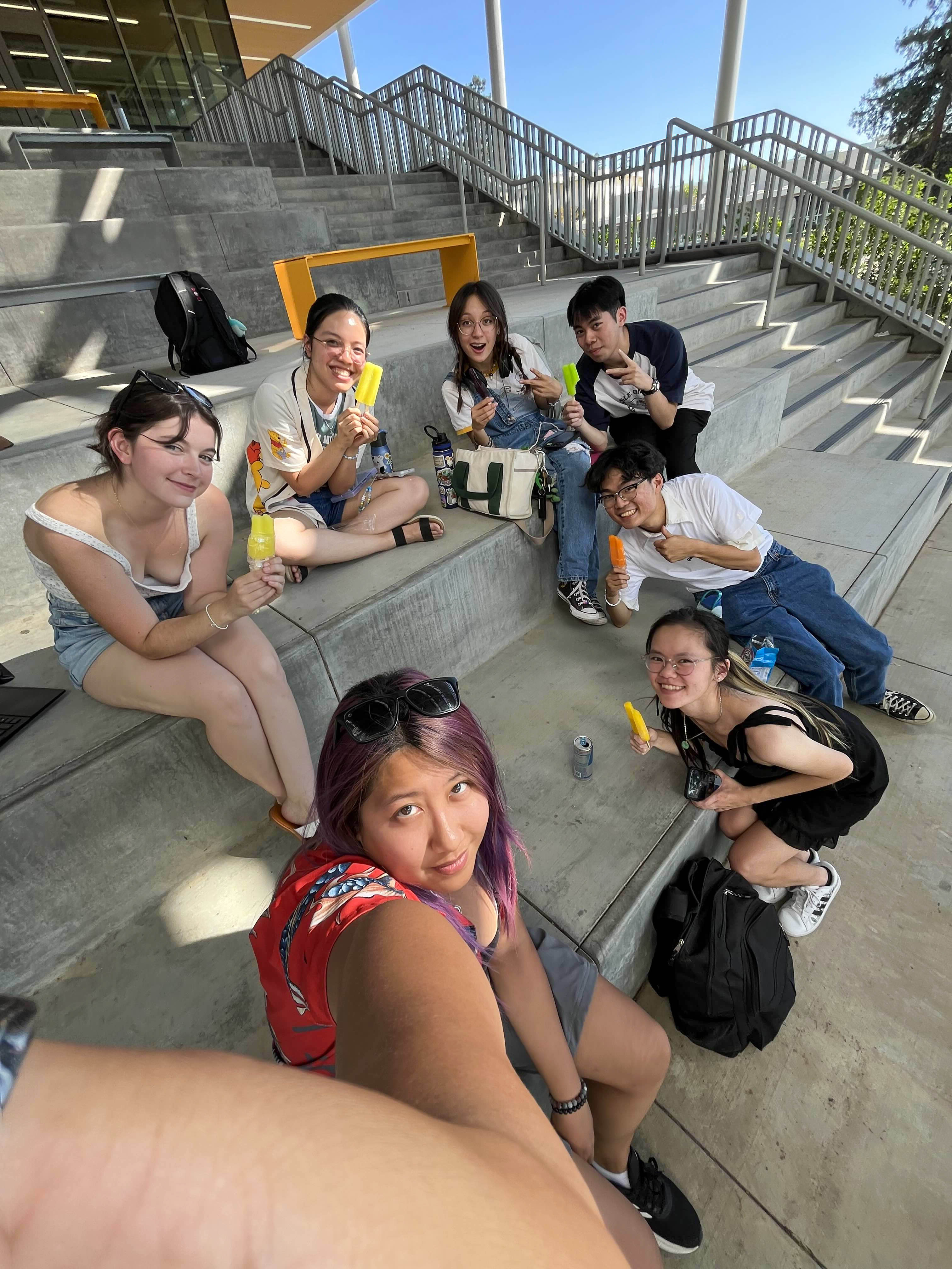 Club members sitting on outdoor steps, smiling up at the camera