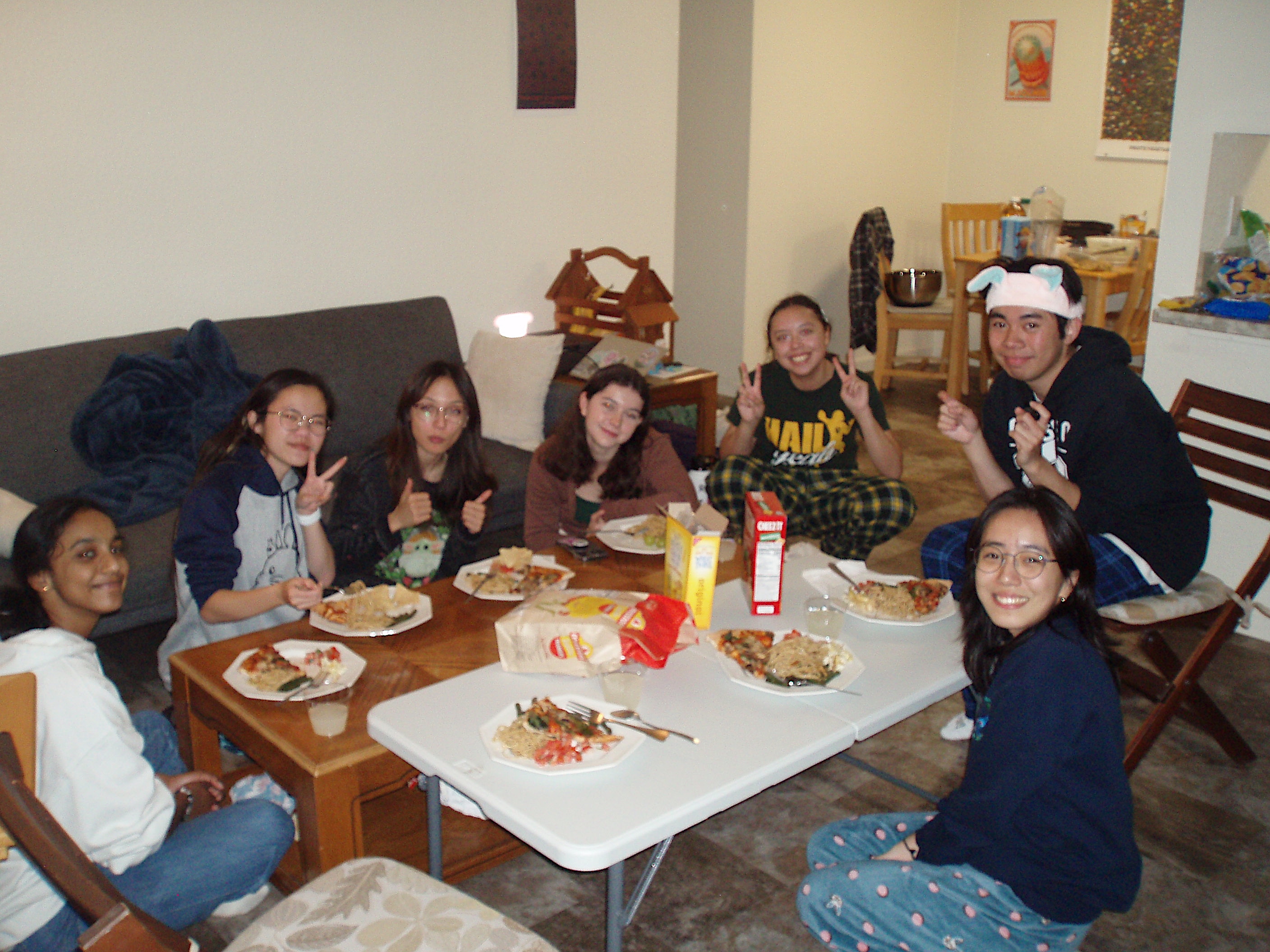 Club members gathered around a table of food, smiling at the camera