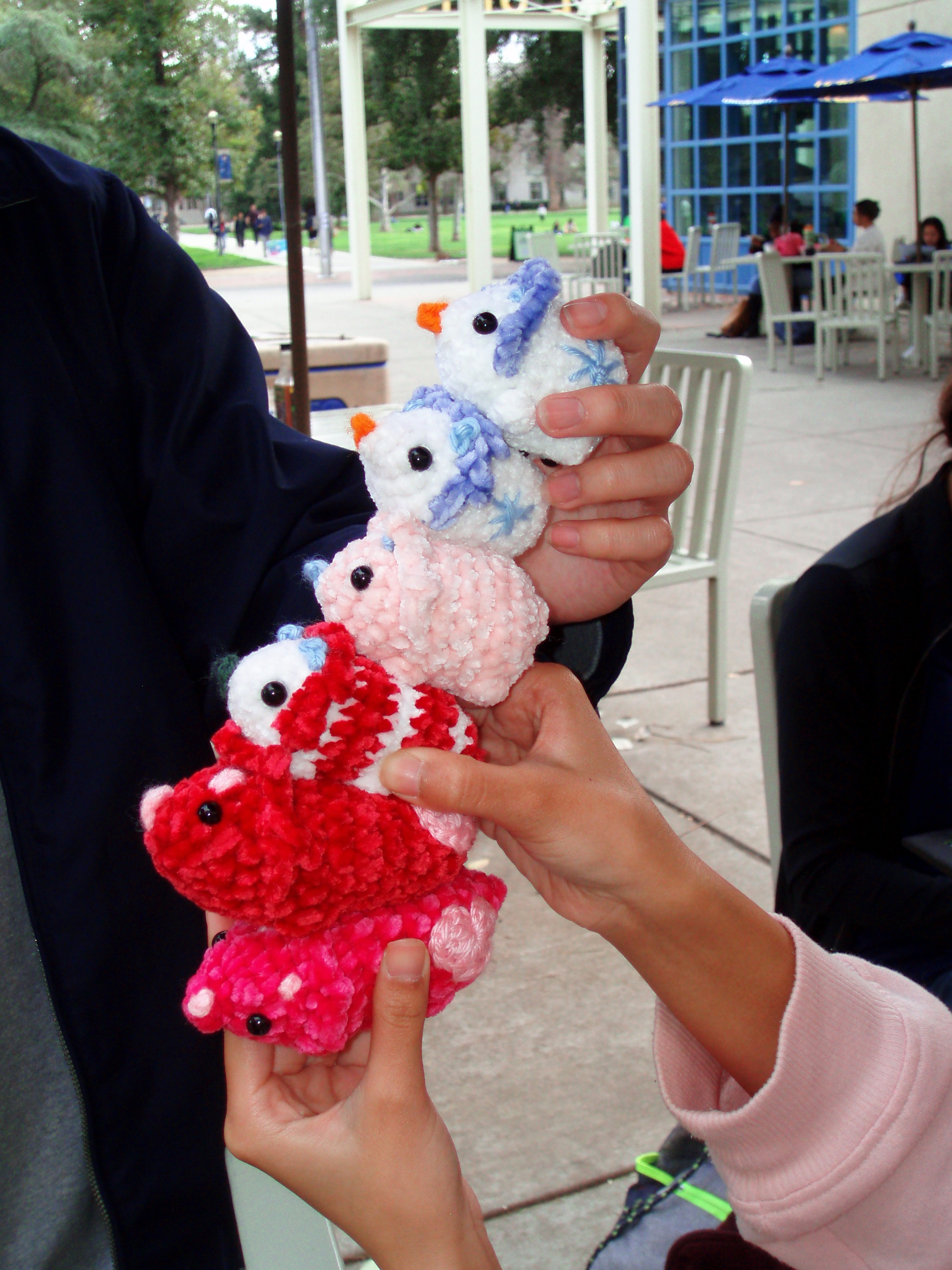 A hand holding several crocheted dinos